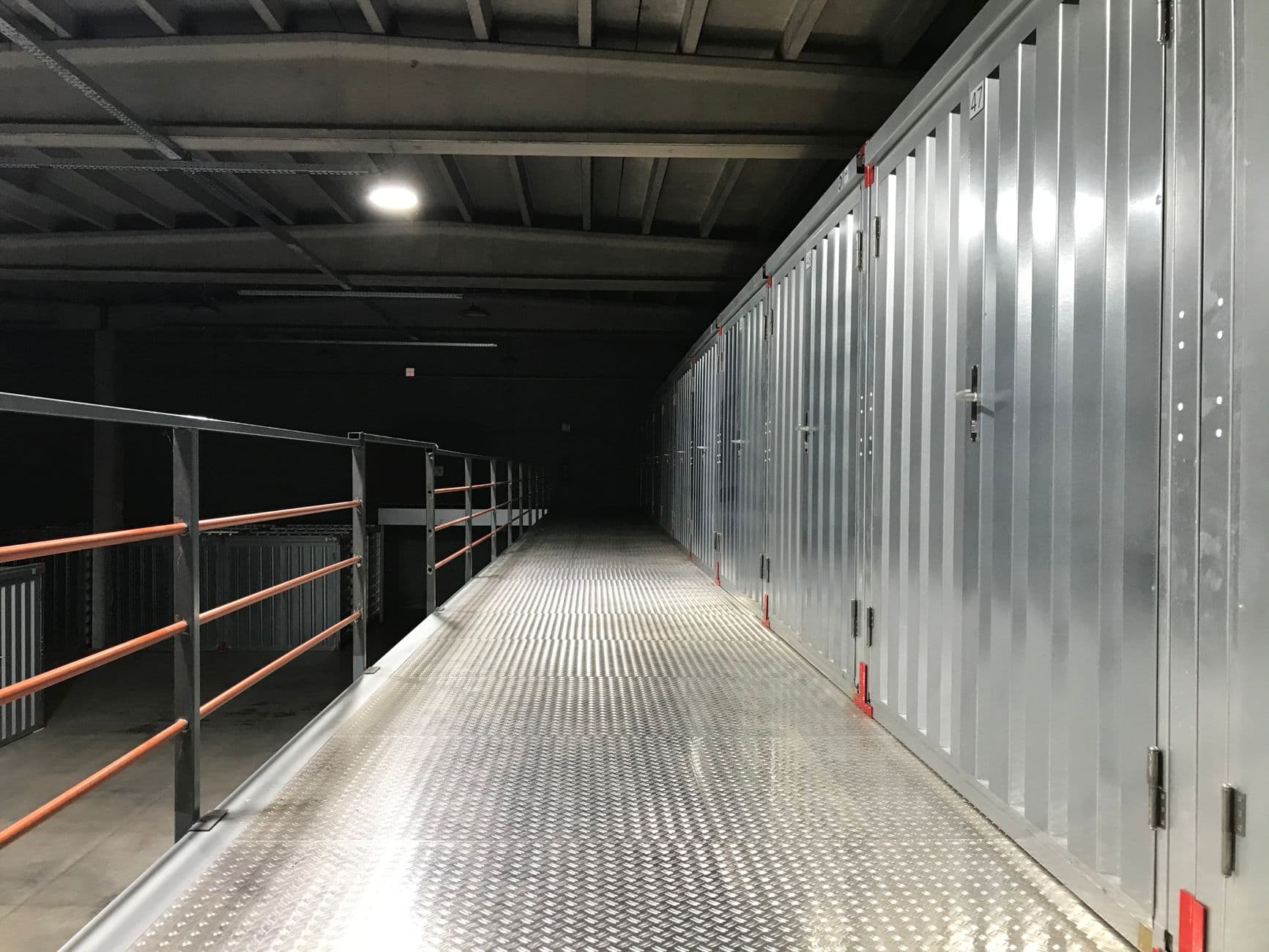 Couloir de boxes de stockage éclairé dans un garde-meuble à Brest