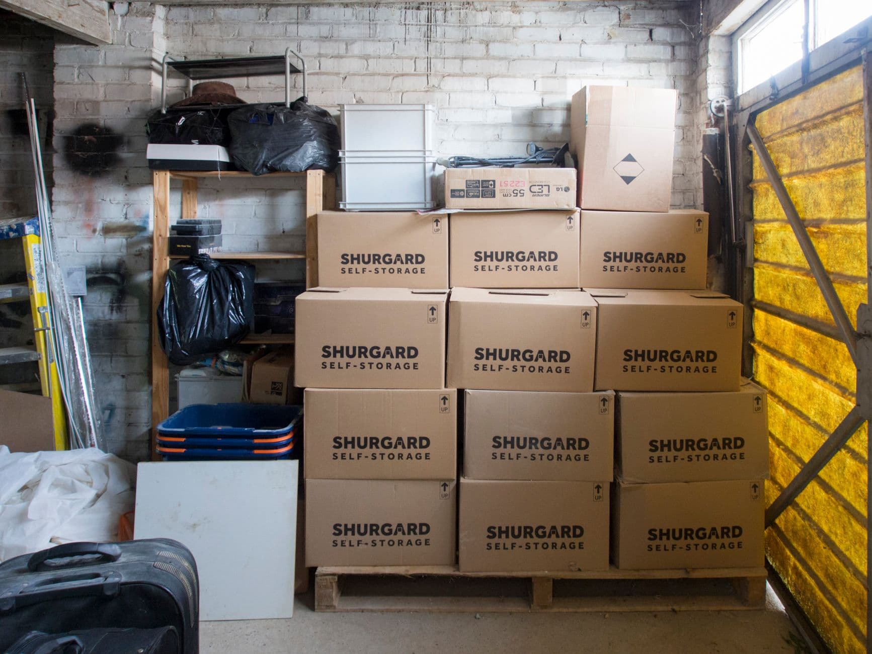 Rangement optimisé dans un box de stockage avec cartons empilés et meubles démontés